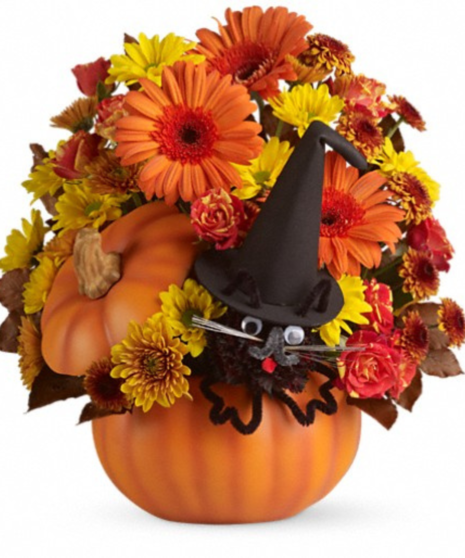 pumpkin vase filled with fall-toned orange and yellow flowers accented with black cat