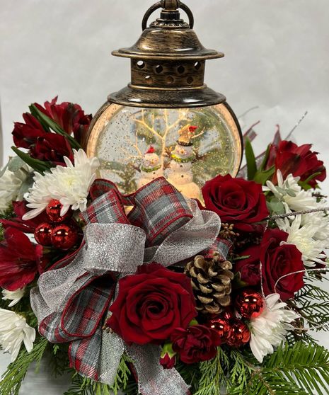 light up holiday snow globe surrounded by fresh holiday flowers