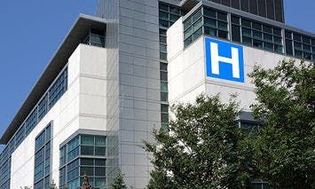 A modern multi-story hospital building with a prominent blue 